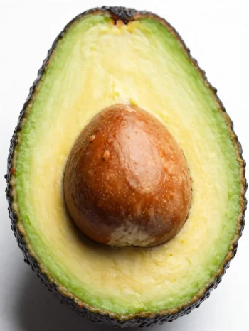 Aguacate fresco cortado con interior verde cremoso sobre superficie de madera