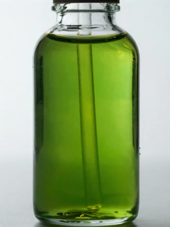 Aceite de aguacate en botella pequeña y cuenco sobre fondo neutro claro