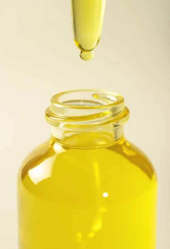 Aceite esencial de limón en frasco pequeño junto a limones frescos