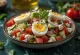 Ensalada Tashkent con huevo cocido, decorada con perejil fresco.