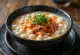 Kongbiji jjigae, alubias blancas, tofu y kimchi en el bol, sabores ricos y decoración de cebolleta