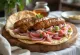 Ćevapi con cebolla, servidos sobre pan pita.