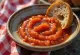 Salsa de mojo rojo dulce en un cuenco, rodeada de trozos de pimiento asado