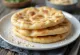 Pan de pita sin gluten horneado dorado, servido en tabla rústica
