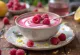 Bebida de yogur frambuesa-limón en vaso, textura cremosa rosa, espolvoreada con ralladura de limón