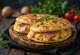 Pita con huevo para el desayuno servida con jamón, pimiento, tomate y queso rallado