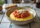 Polenta cremosa servida con salsa de tomate en plato hondo