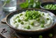 Raita de guisantes servida, decorada con menta fresca y guisantes