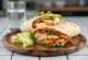 Wrap club sándwich con pechuga de pollo, bacon, queso y tomate, servido cortado por la mitad